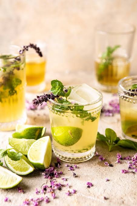 mocktail with citrus, basil, and non-alcoholic sparkling tea in a glass surrounded by aromatics