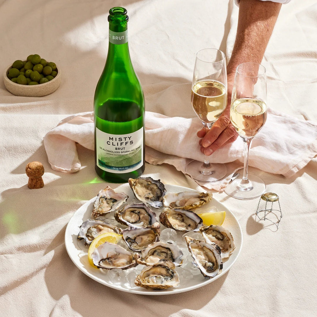 person enjoying misty cliffs non-alcohlic sparkling brut wine in a bed with oysters